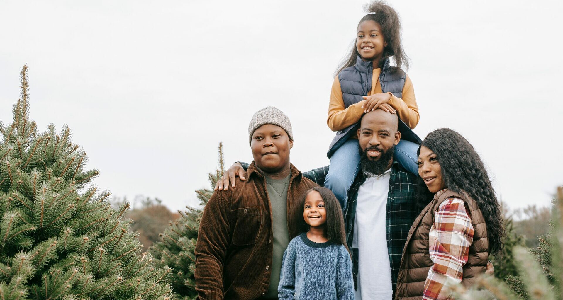 A family of five at a pine tree farm in the winter.