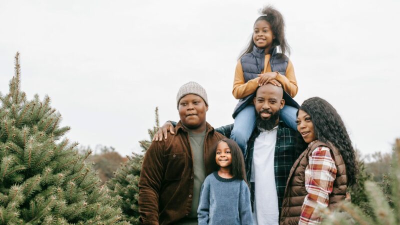 A family of five at a pine tree farm in the winter.