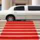 A white limo parked in front of a red capret that is rolled out over a set of stairs.