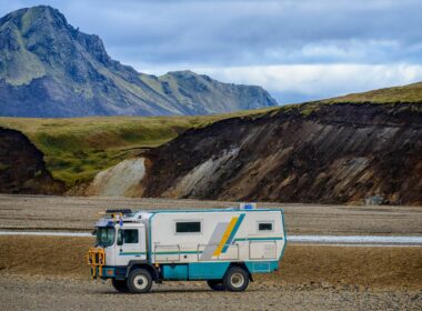 An all terrain vehicle converted into a camper with mountains in the background.