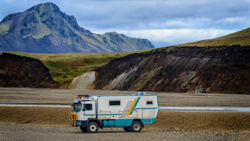 An all terrain vehicle converted into a camper with mountains in the background.