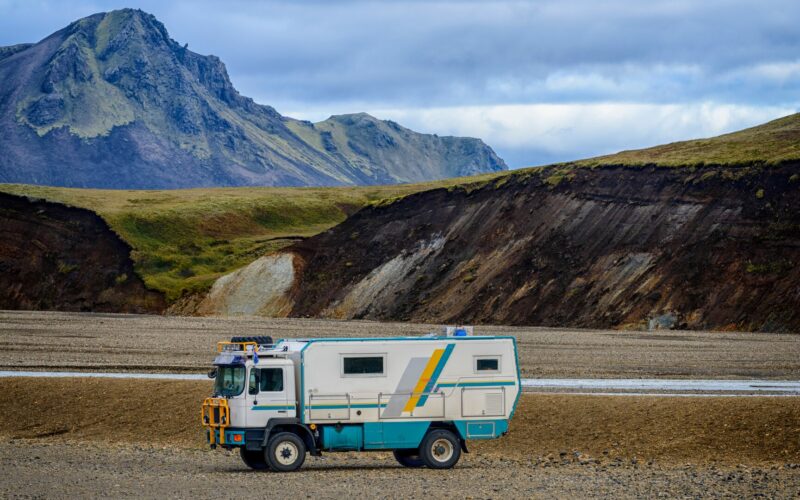 An all terrain vehicle converted into a camper with mountains in the background.