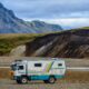 An all terrain vehicle converted into a camper with mountains in the background.