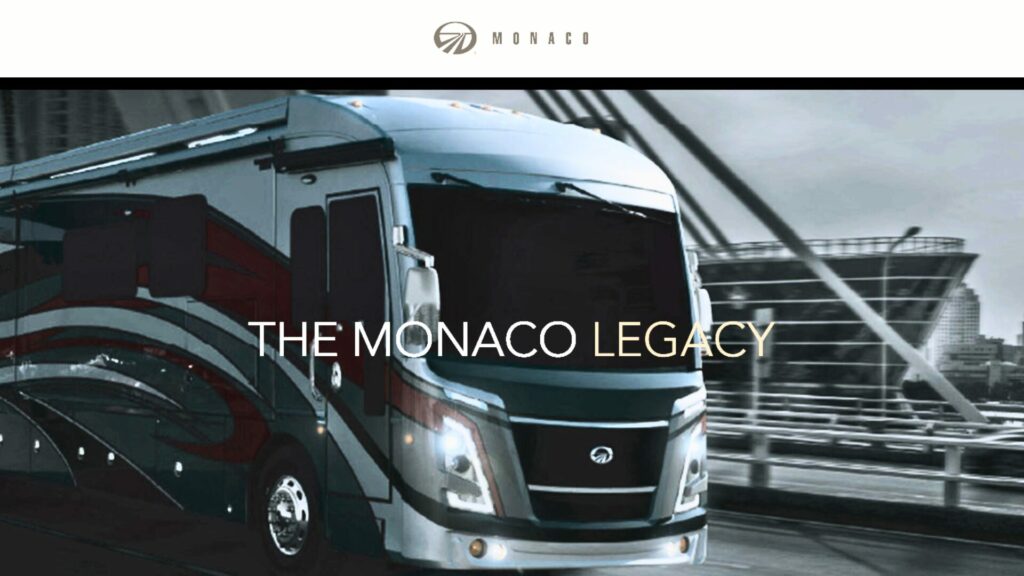 One of Monaco's, a brand under the REV Group, motorhomes driving over a bridge with a city landscape in the background.