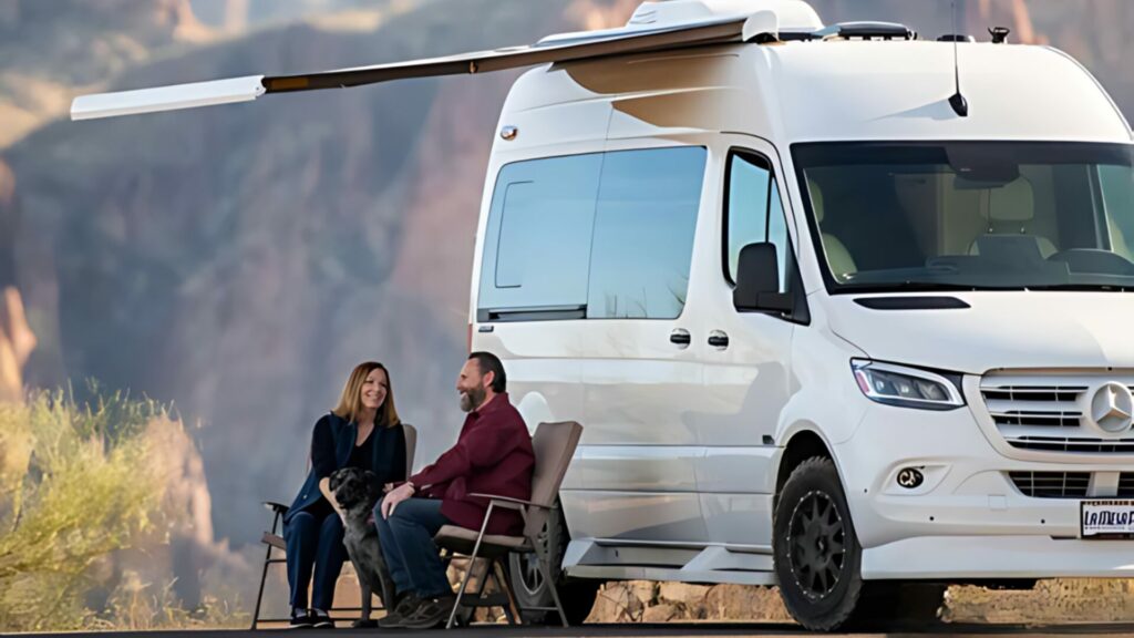 A Midwest Automotive Design camper van with a couple and their dog sitting outside in outdoor chairs.