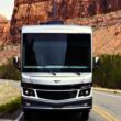 One of REV Group's motorhomes driving through a red rocky desert landscape on a road.