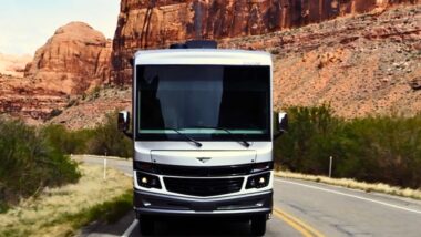 One of REV Group's motorhomes driving through a red rocky desert landscape on a road.