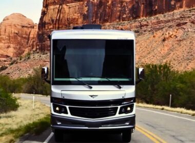 One of REV Group's motorhomes driving through a red rocky desert landscape on a road.